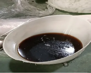 A light-colored aluminum pan with dark paint pooled in the bottom.