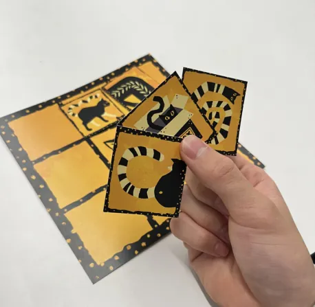 A hand holding a fan of special cards above the printed map.